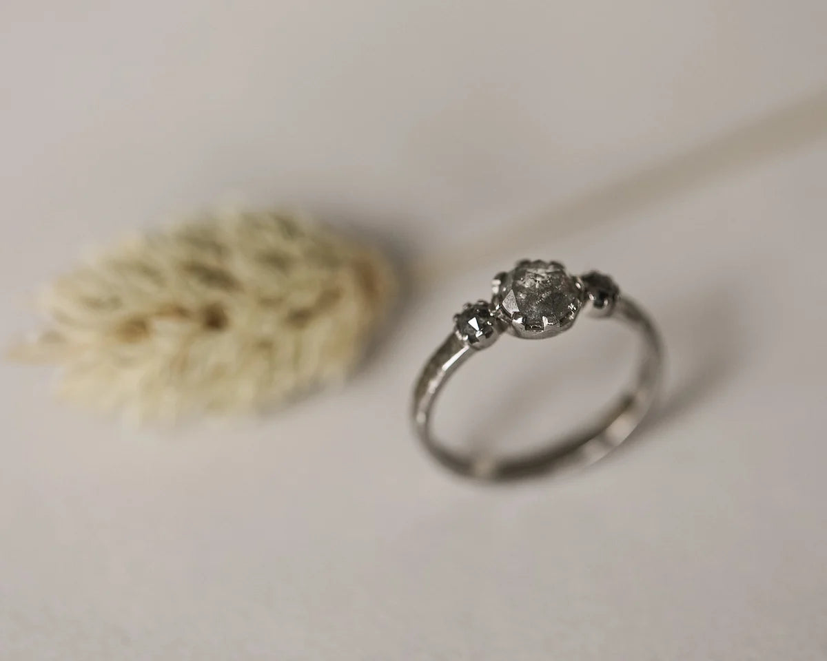 Angled view of pale grey salt and pepper diamond trilogy ring