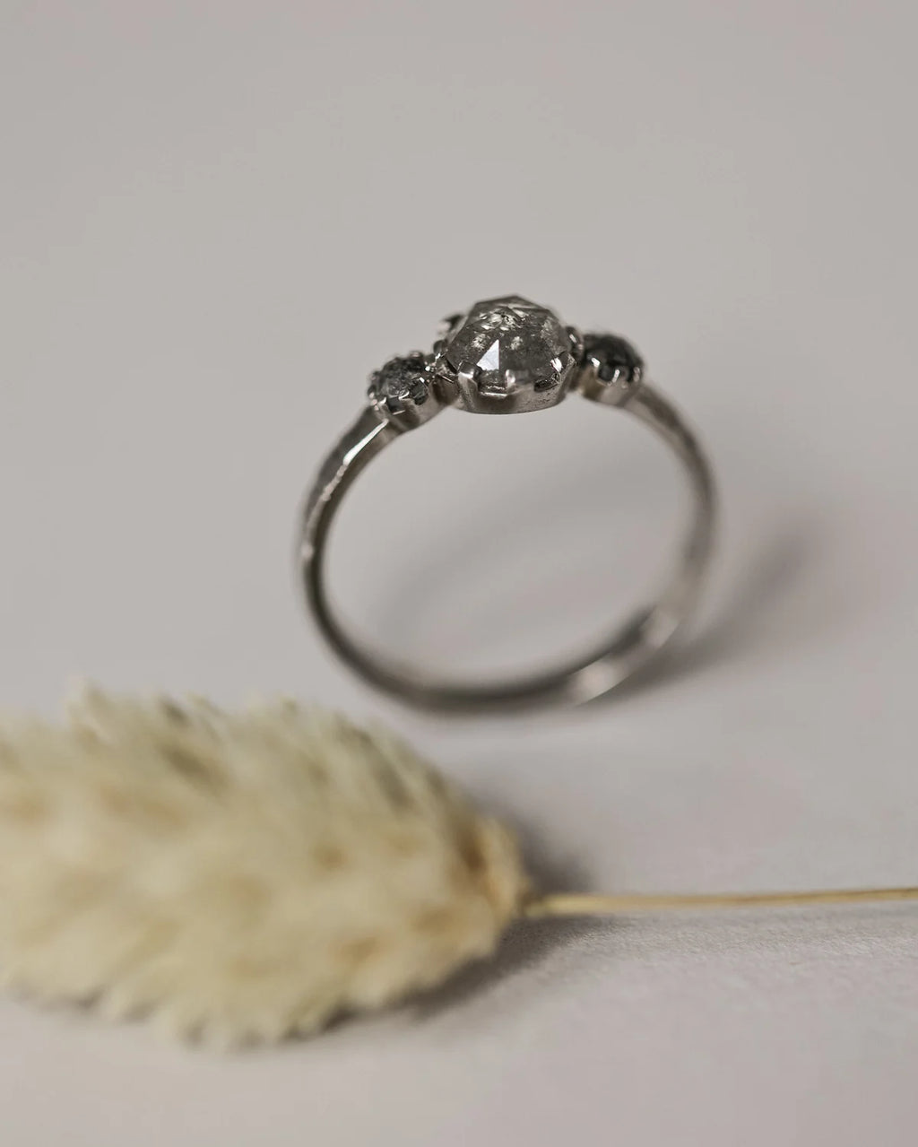 Vertical view of platinum pale grey diamond trilogy ring