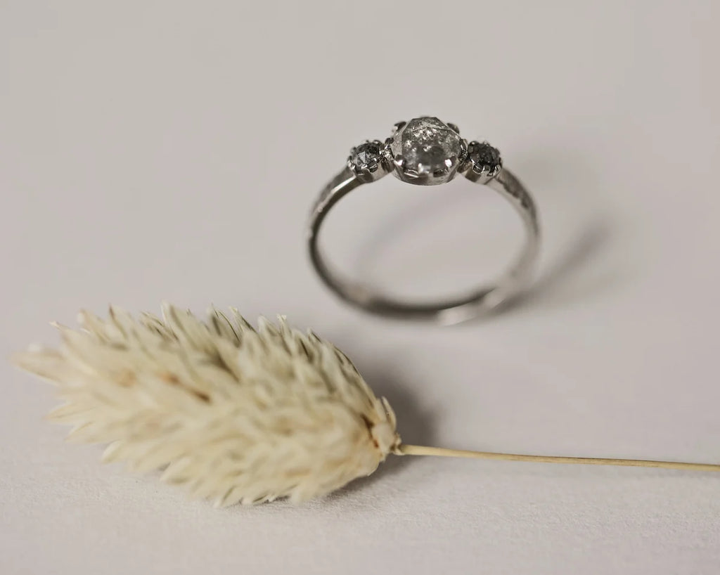 Platinum pale grey diamond trilogy ring styled with dried flower