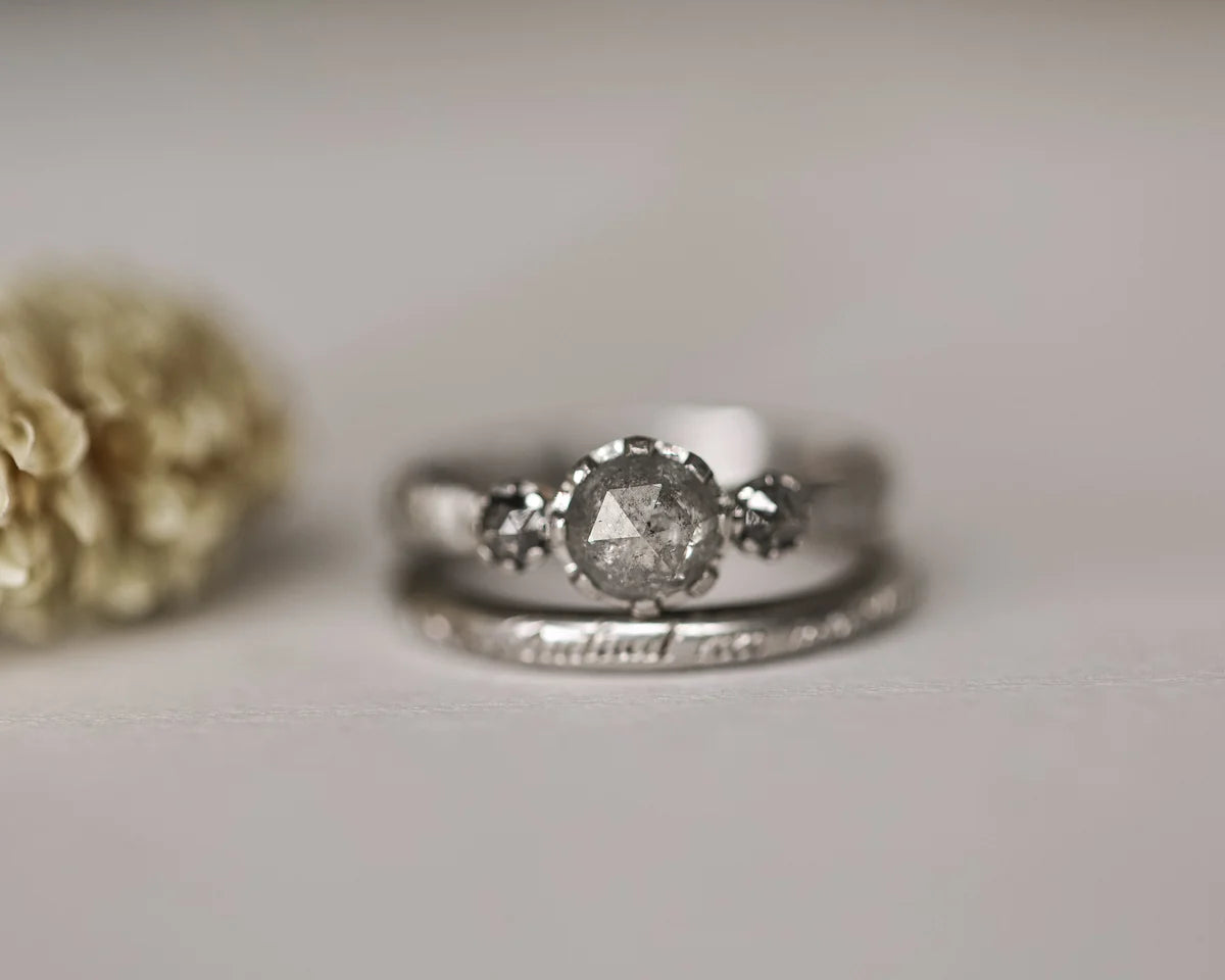 Angled close-up of platinum salt and pepper diamond trilogy ring