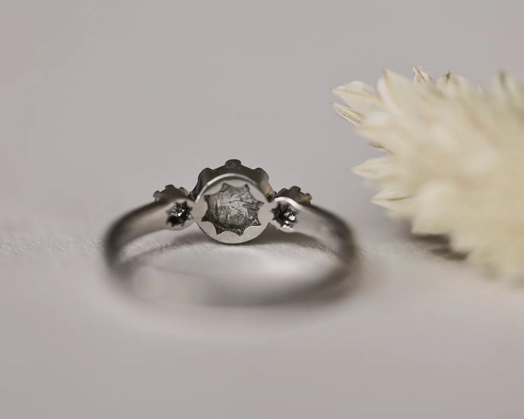 Low front view of pale grey diamond trilogy ring with horn texture band