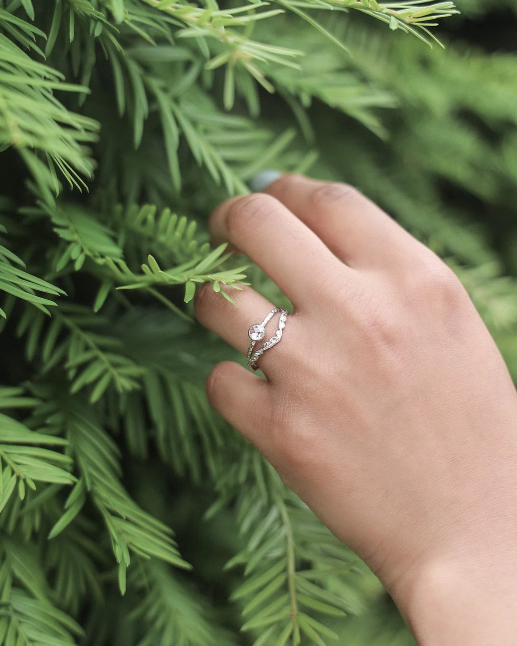 Platinum rose-cut diamond ring worn on hand with greenery