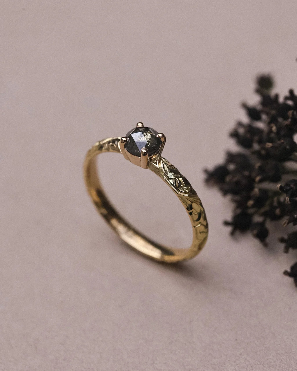 Side view of floral engraved yellow gold ring with grey rose-cut diamond