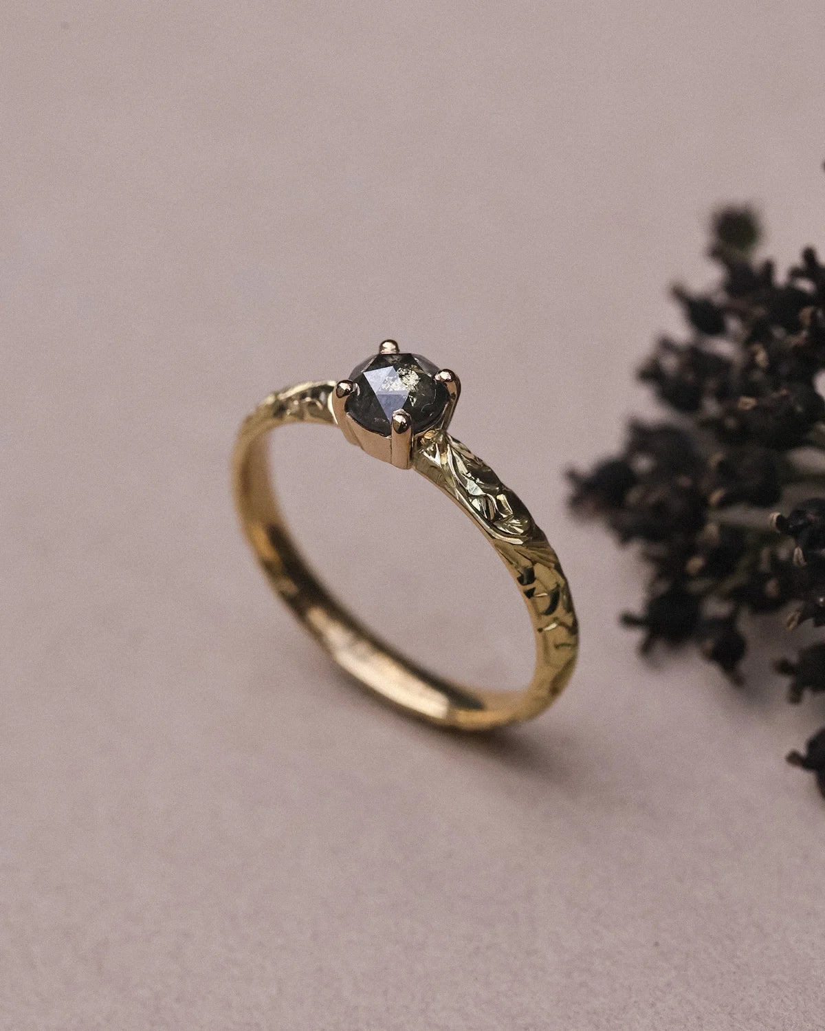 Side view of floral engraved yellow gold ring with grey rose-cut diamond