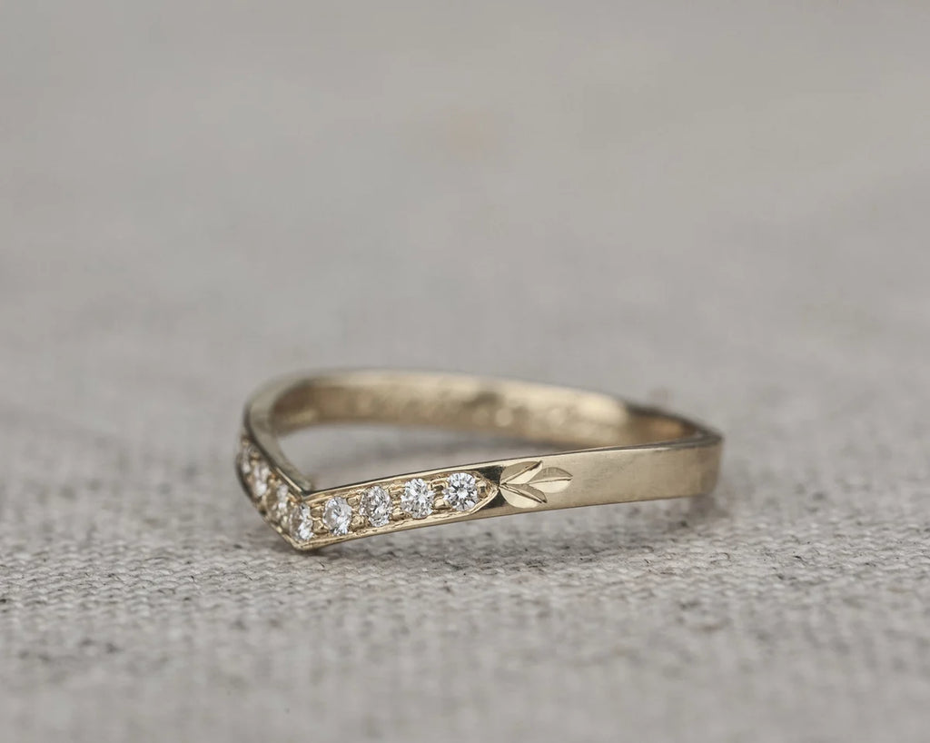 Angled view of white gold diamond wishbone ring with leaf engraving