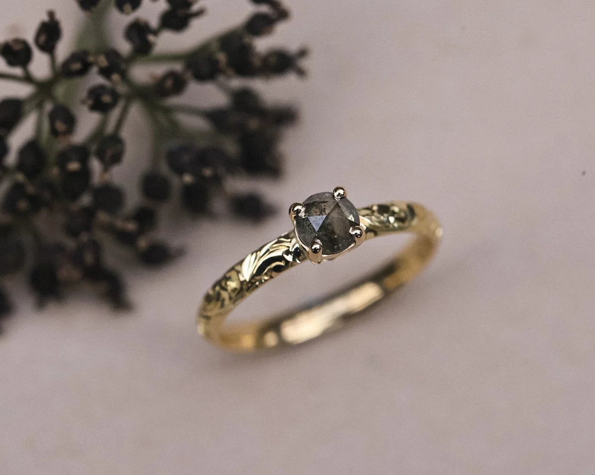Angled view of handmade yellow gold ring with dark grey diamond