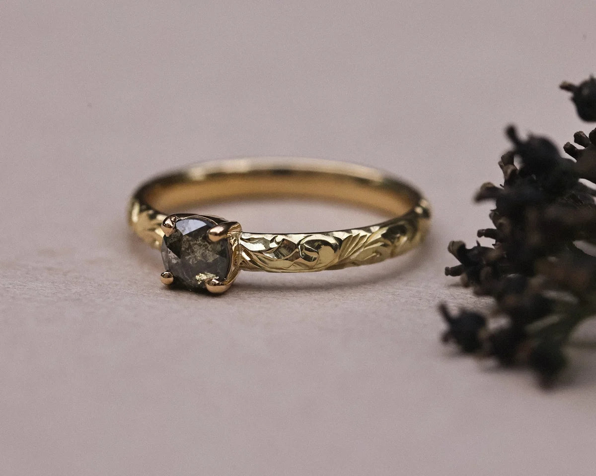 Front view of dark grey rose-cut diamond ring with engraved floral band