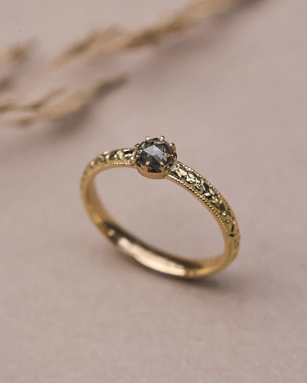 Close-up of natural grey rose-cut diamond with orange blossom engraved band