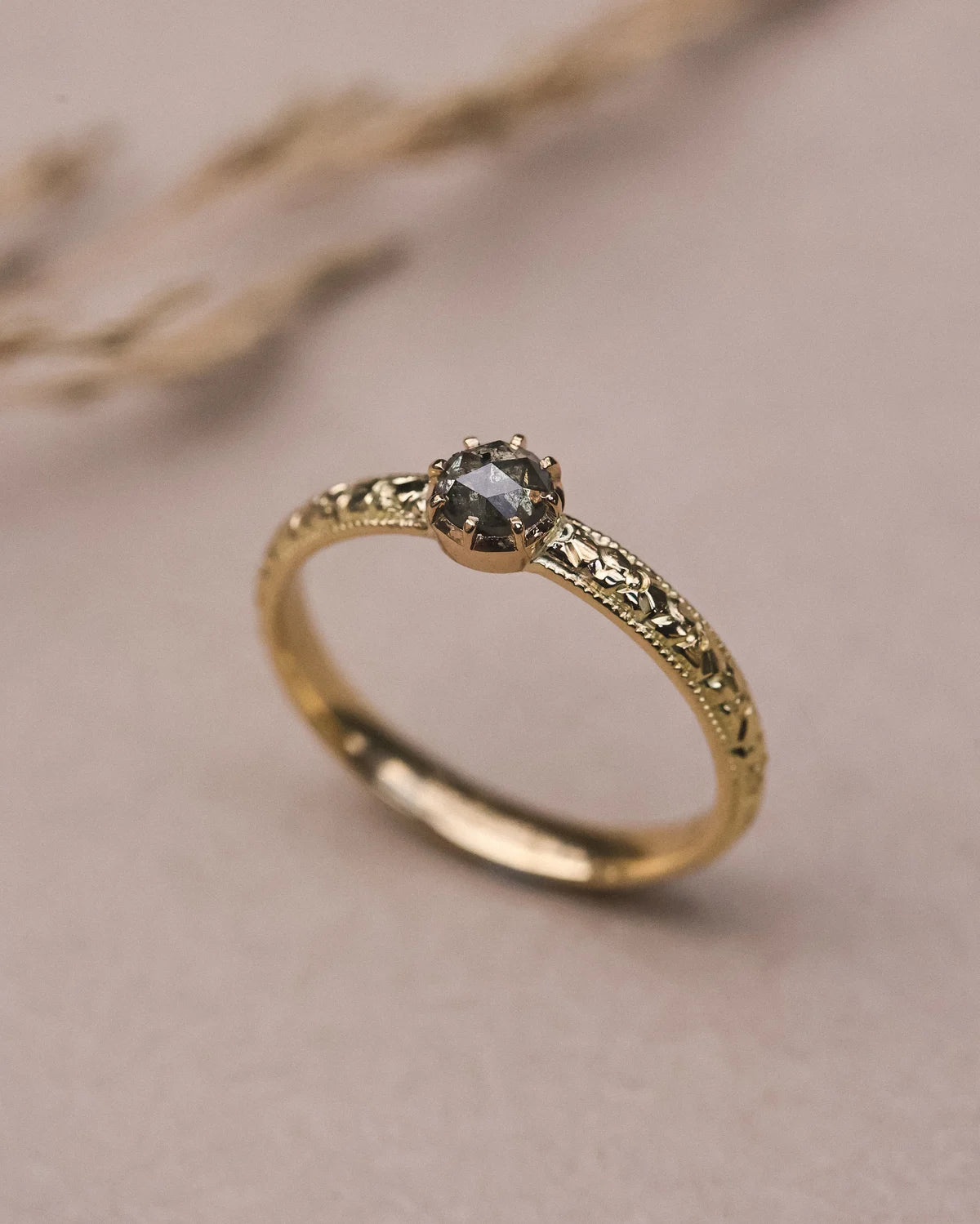 Close-up of natural grey rose-cut diamond with orange blossom engraved band