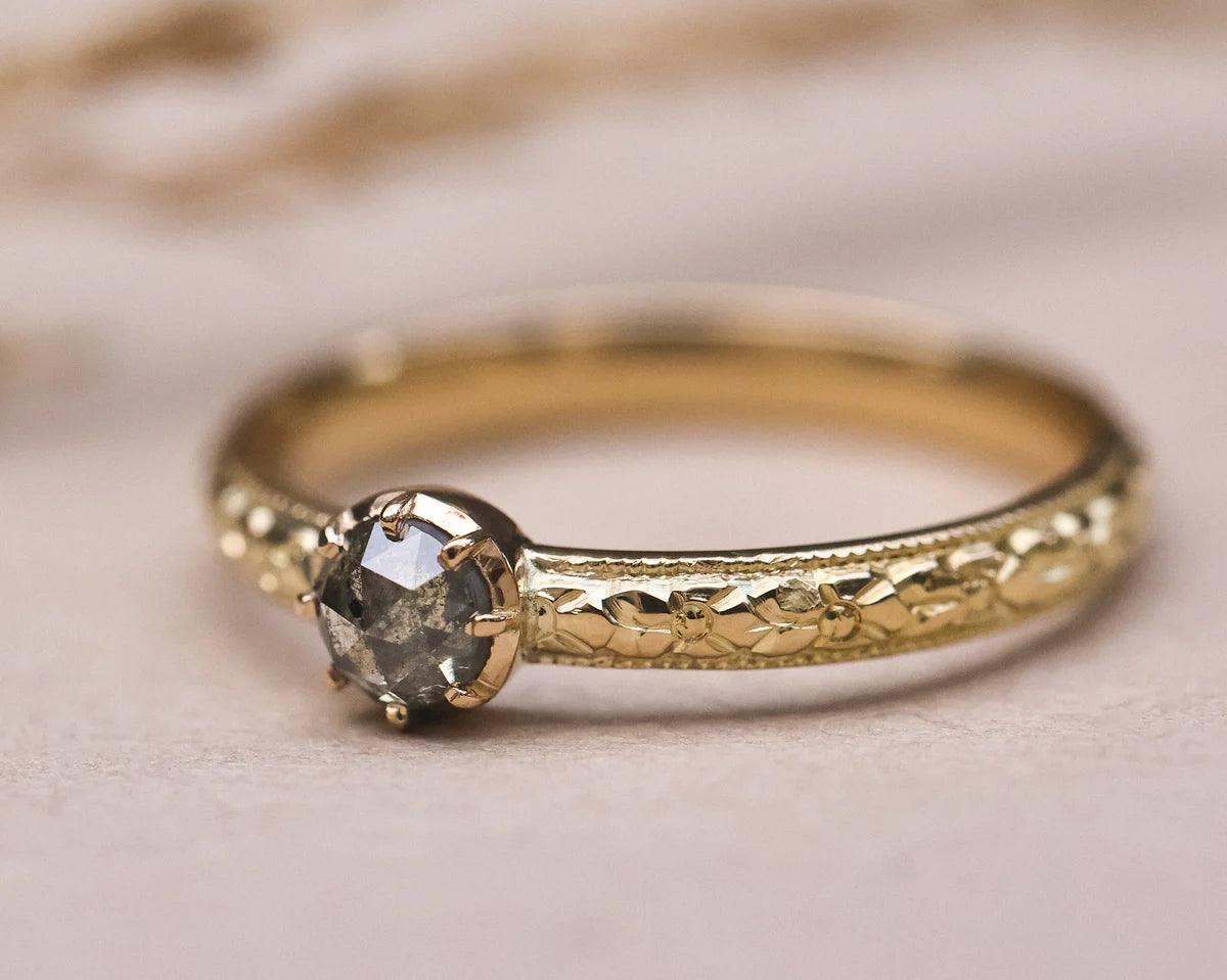 Side view of grey rose-cut diamond ring with hand engraved orange blossom band