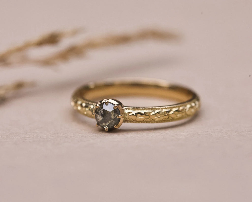 Low profile view of grey rose-cut diamond ring with engraved gold band