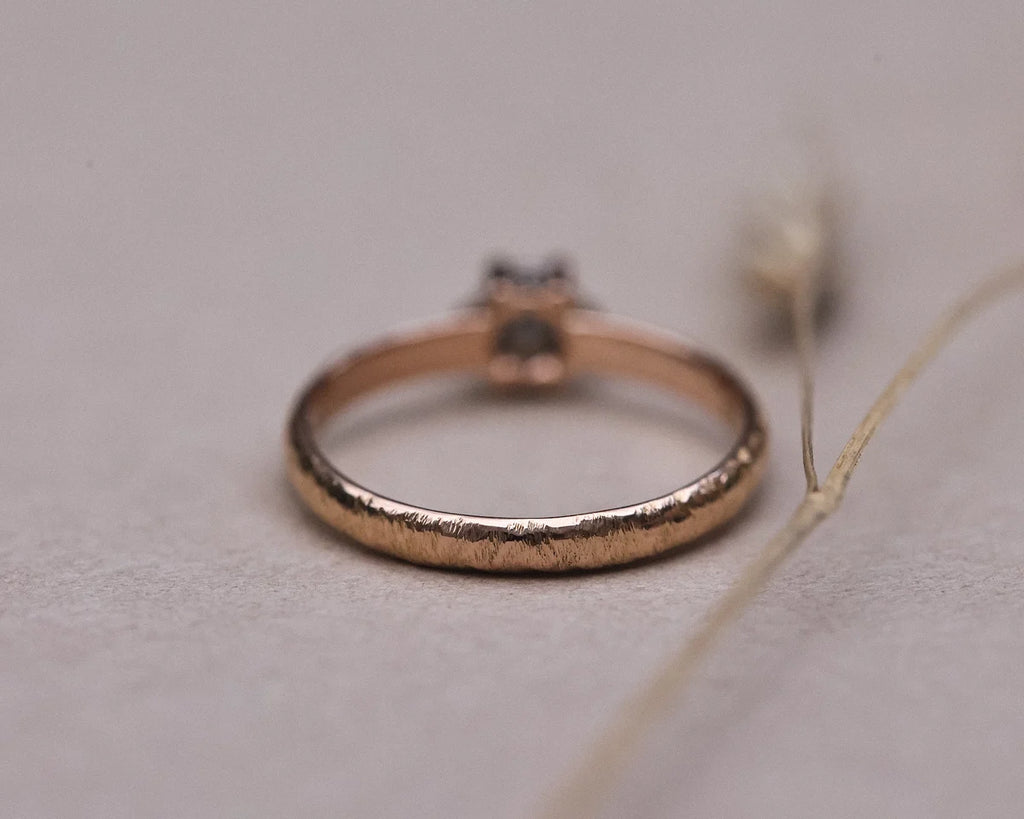 Side profile of grey rose-cut diamond ring with textured rose gold band