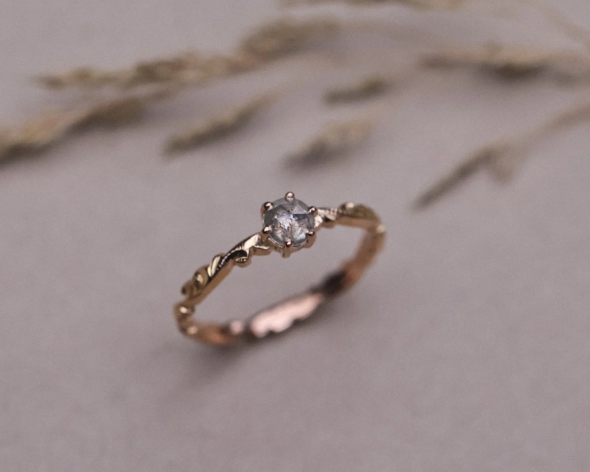 Close-up of handmade rose gold floral ring with pale grey diamond