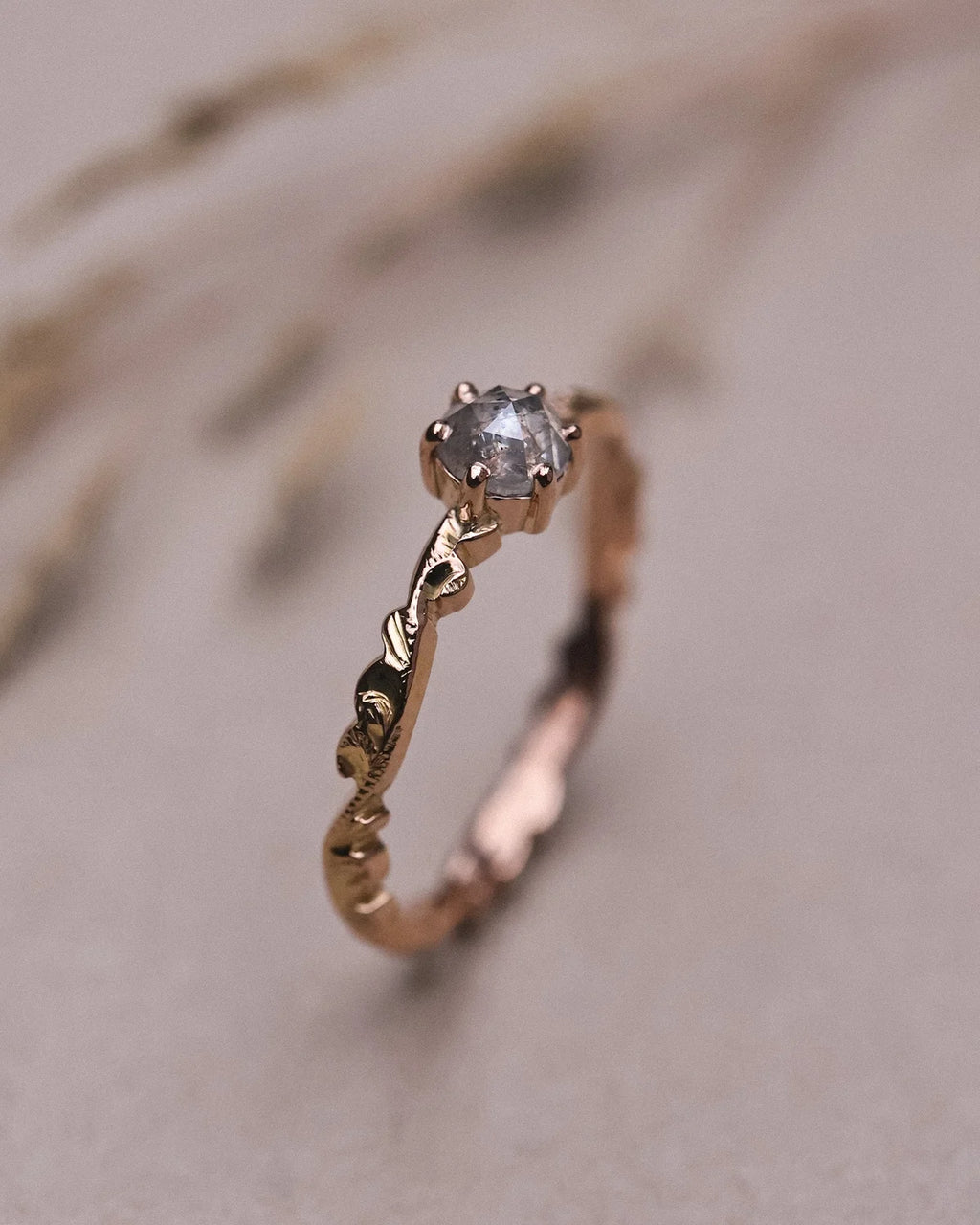 Side profile of pale grey rose-cut diamond ring with floral carved band