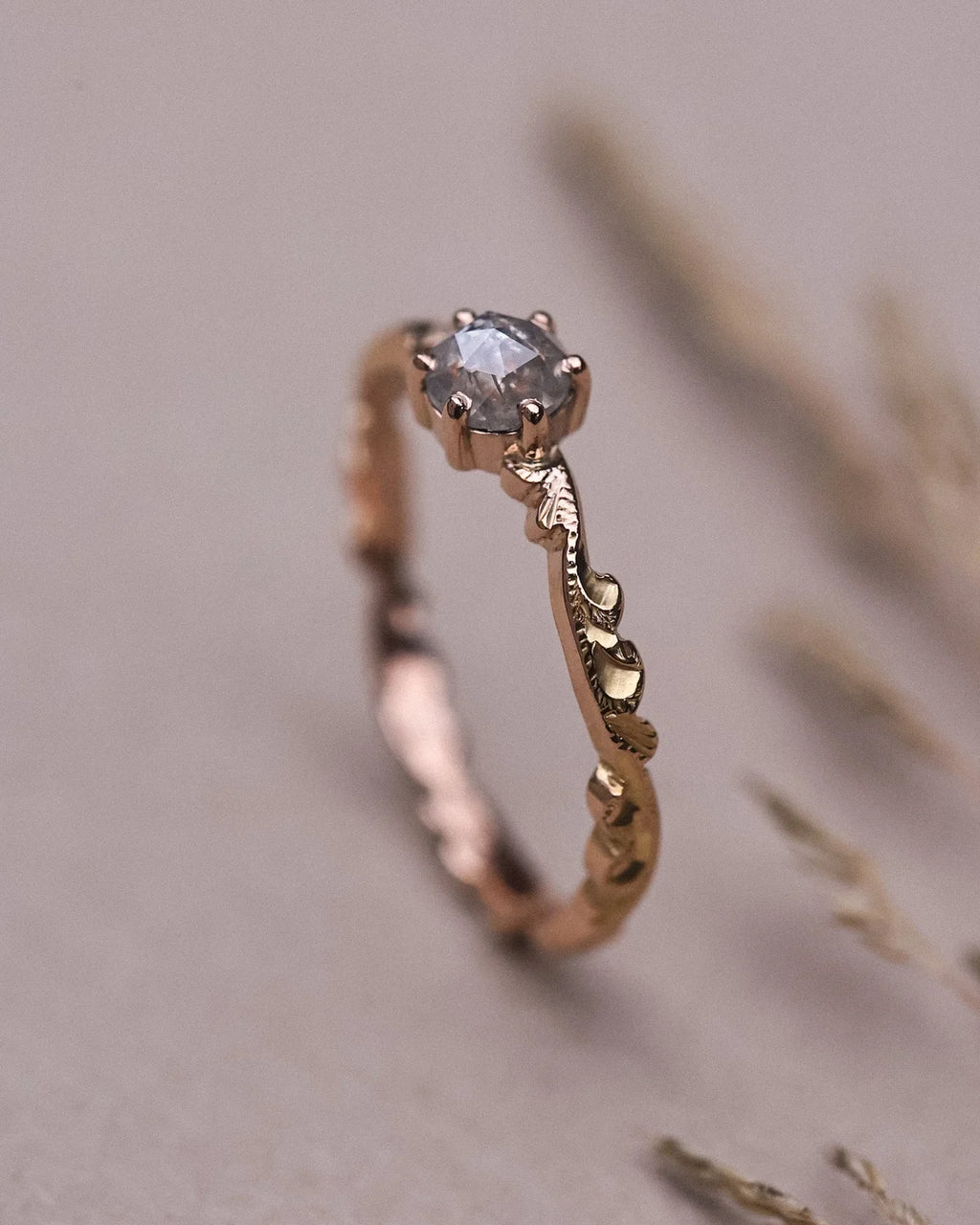 Portrait view of pale grey diamond ring with carved rose gold band