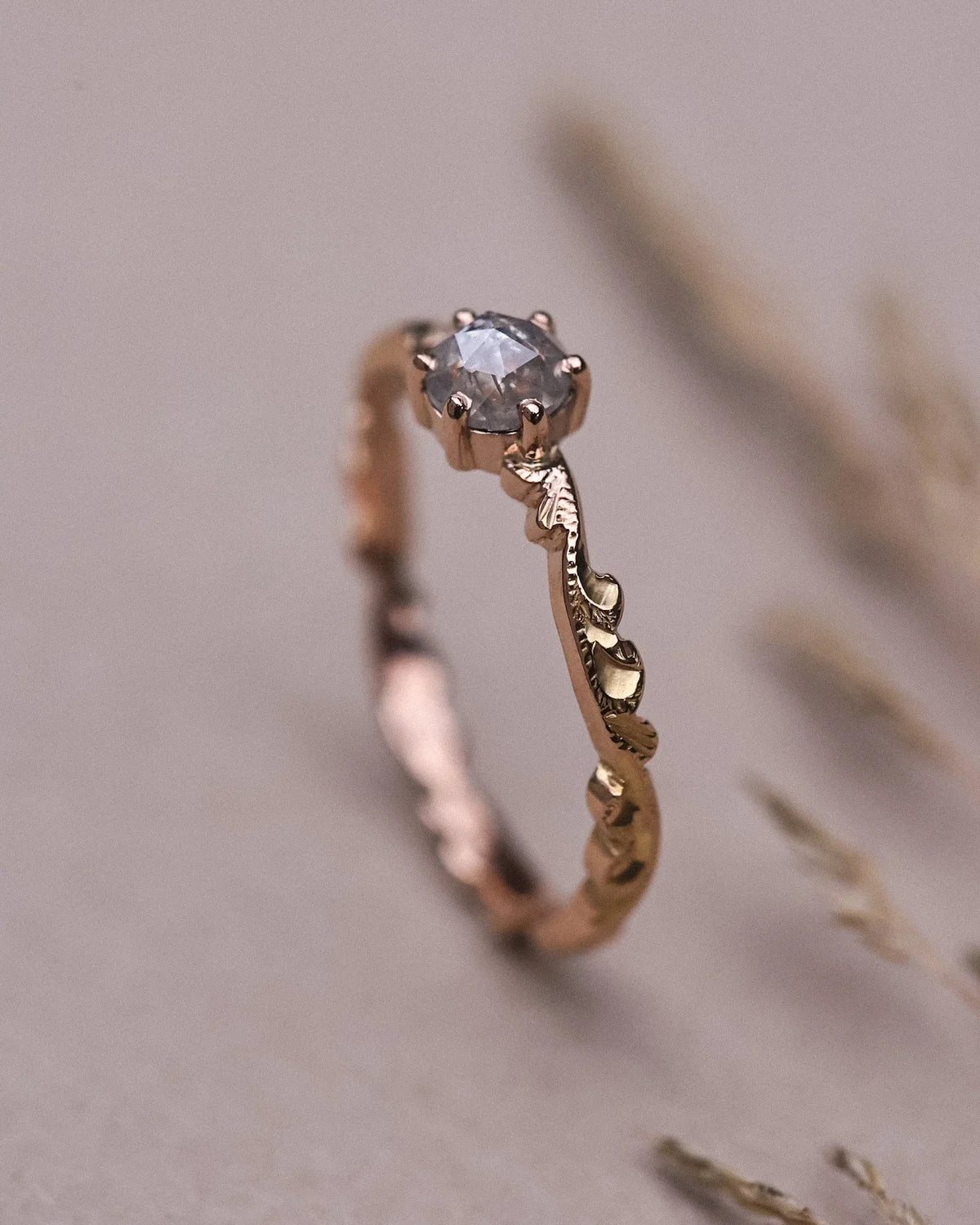 Portrait view of pale grey diamond ring with carved rose gold band