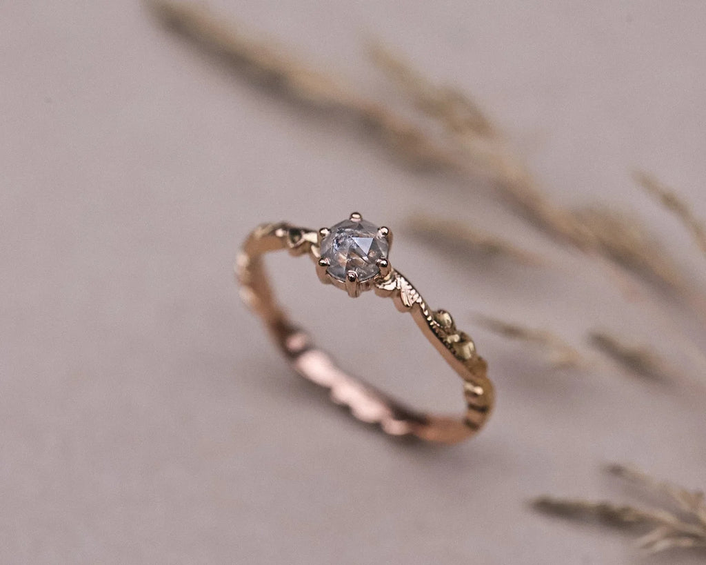Angled view of pale grey rose-cut diamond ring with floral carved band