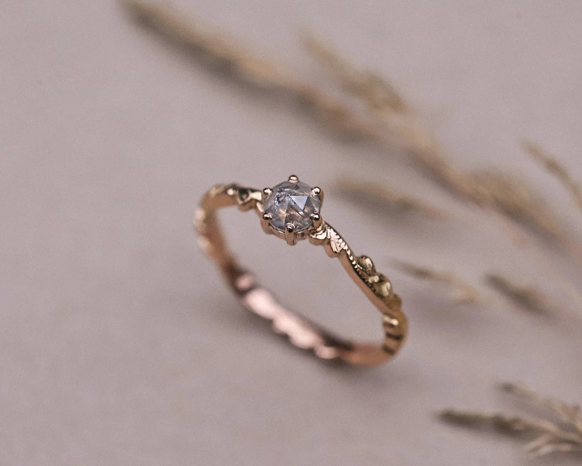 Angled view of pale grey rose-cut diamond ring with floral carved band
