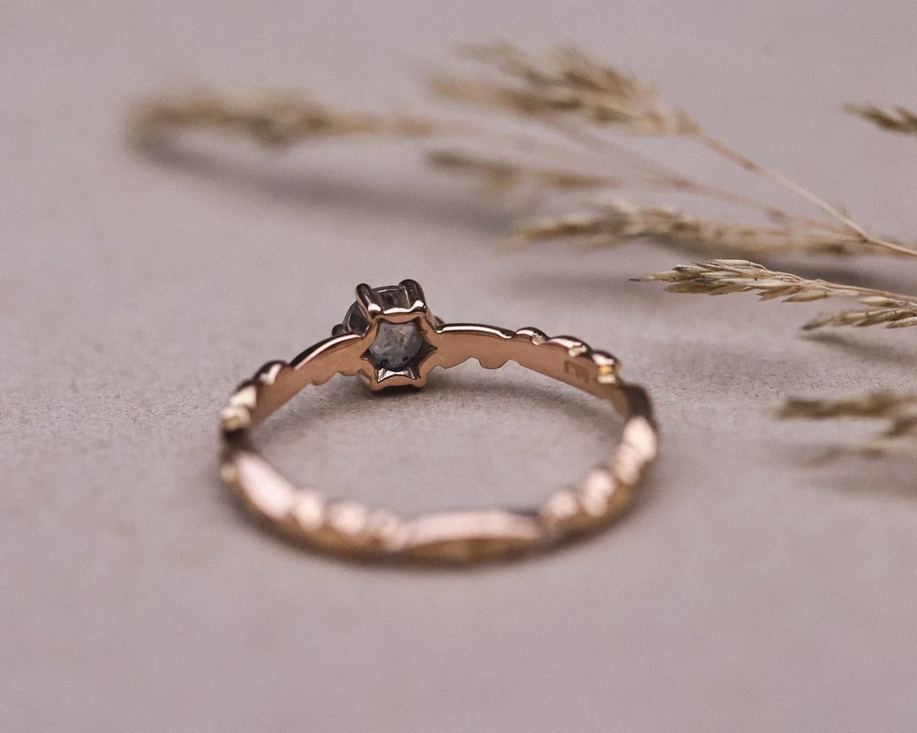 Low front view of pale grey diamond ring with carved rose gold band