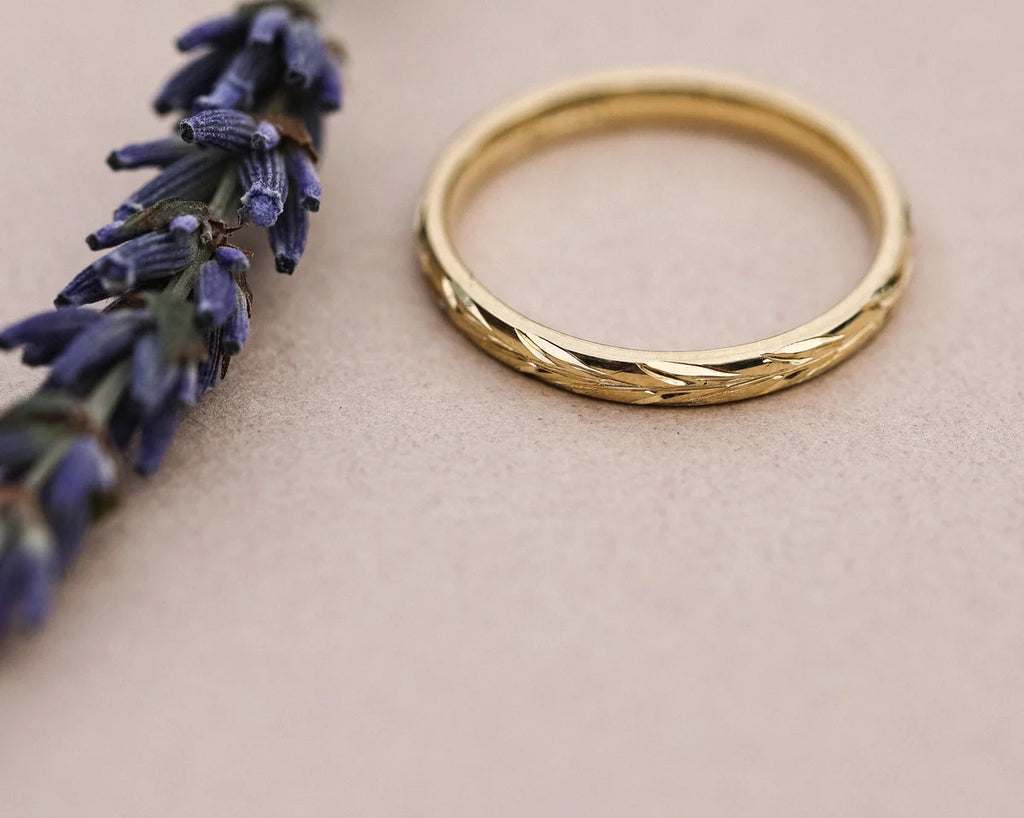 Close-up of hand engraved olive leaf detail on 18ct yellow gold band