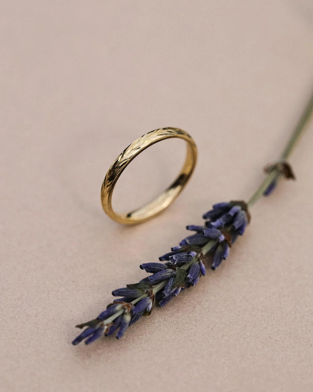 Side profile of handmade olive leaf engraved wedding ring in yellow gold