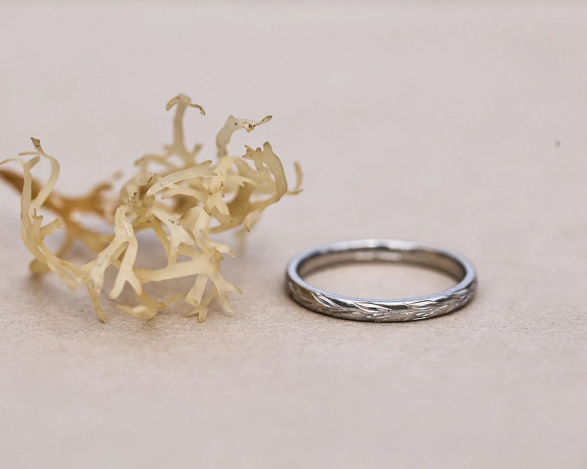 Platinum olive leaf wedding ring styled with pale botanical detail