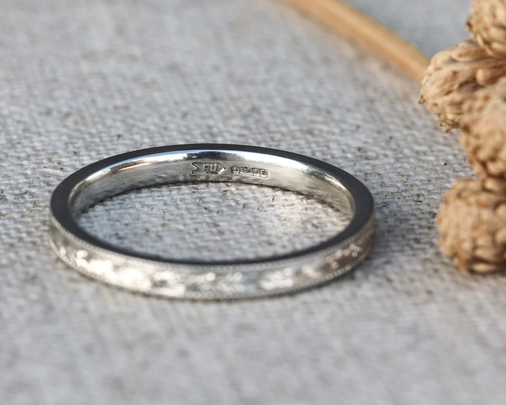 Silver ring with '925' stamp on a textured surface