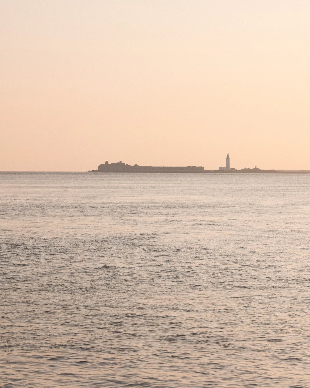 Horizon with a building and a lighthouse on a pinkish sky