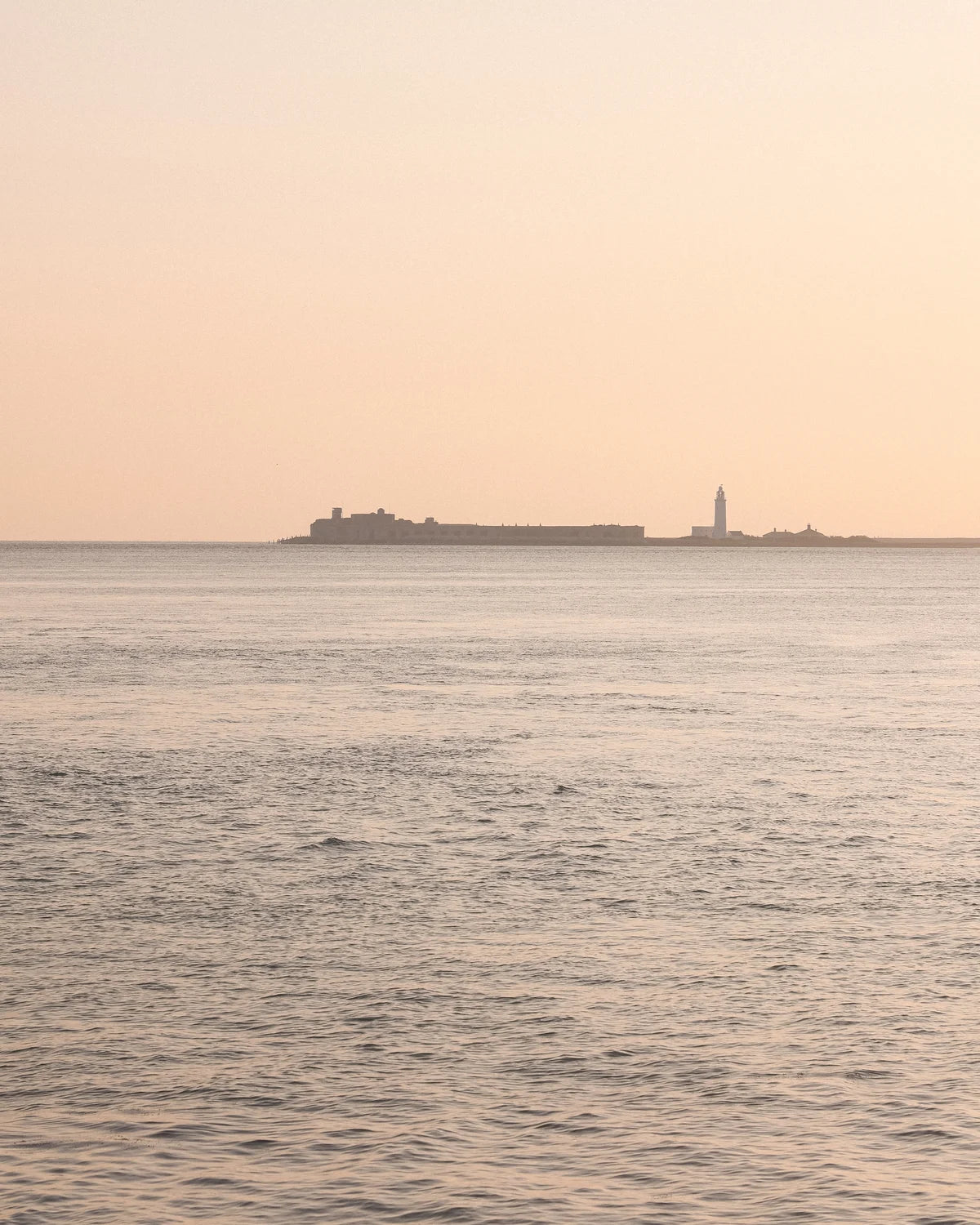 Horizon with a building and a lighthouse on a pinkish sky