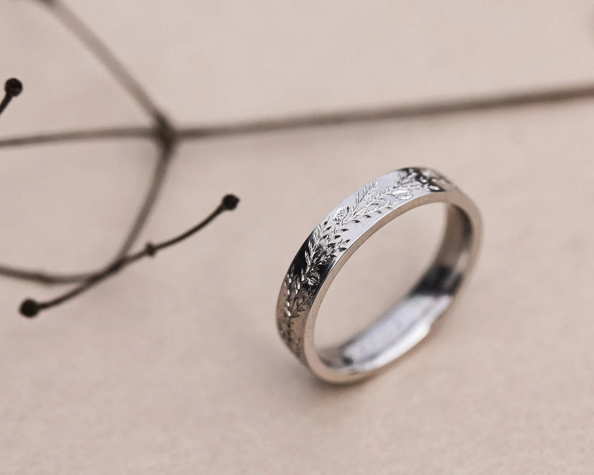 Side view of 4mm platinum wedding ring with hand engraved fir motif