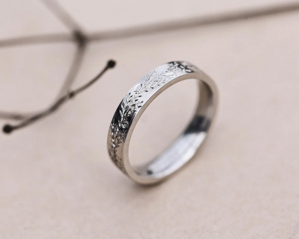 Close-up of flat court platinum ring with fir engraving