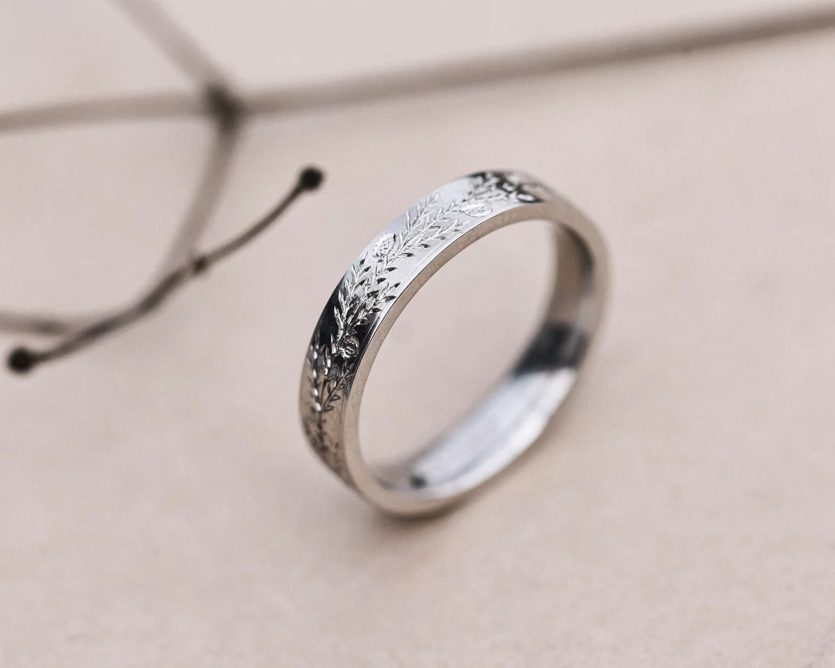 Close-up of flat court platinum ring with fir engraving