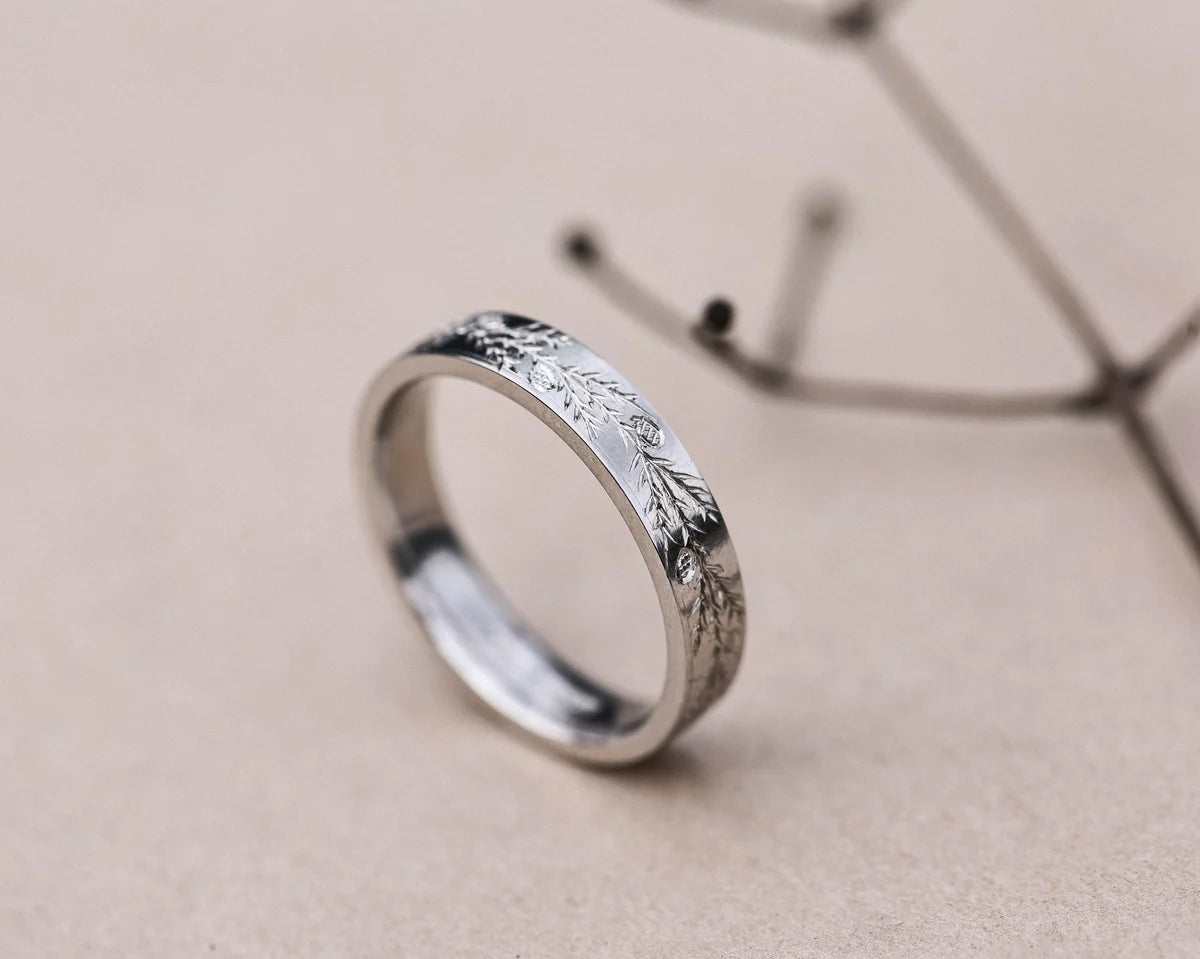 Angled view of platinum fir engraved wedding ring