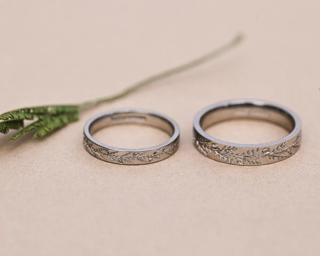 Two platinum flat court wedding rings with hand engraved fir motif