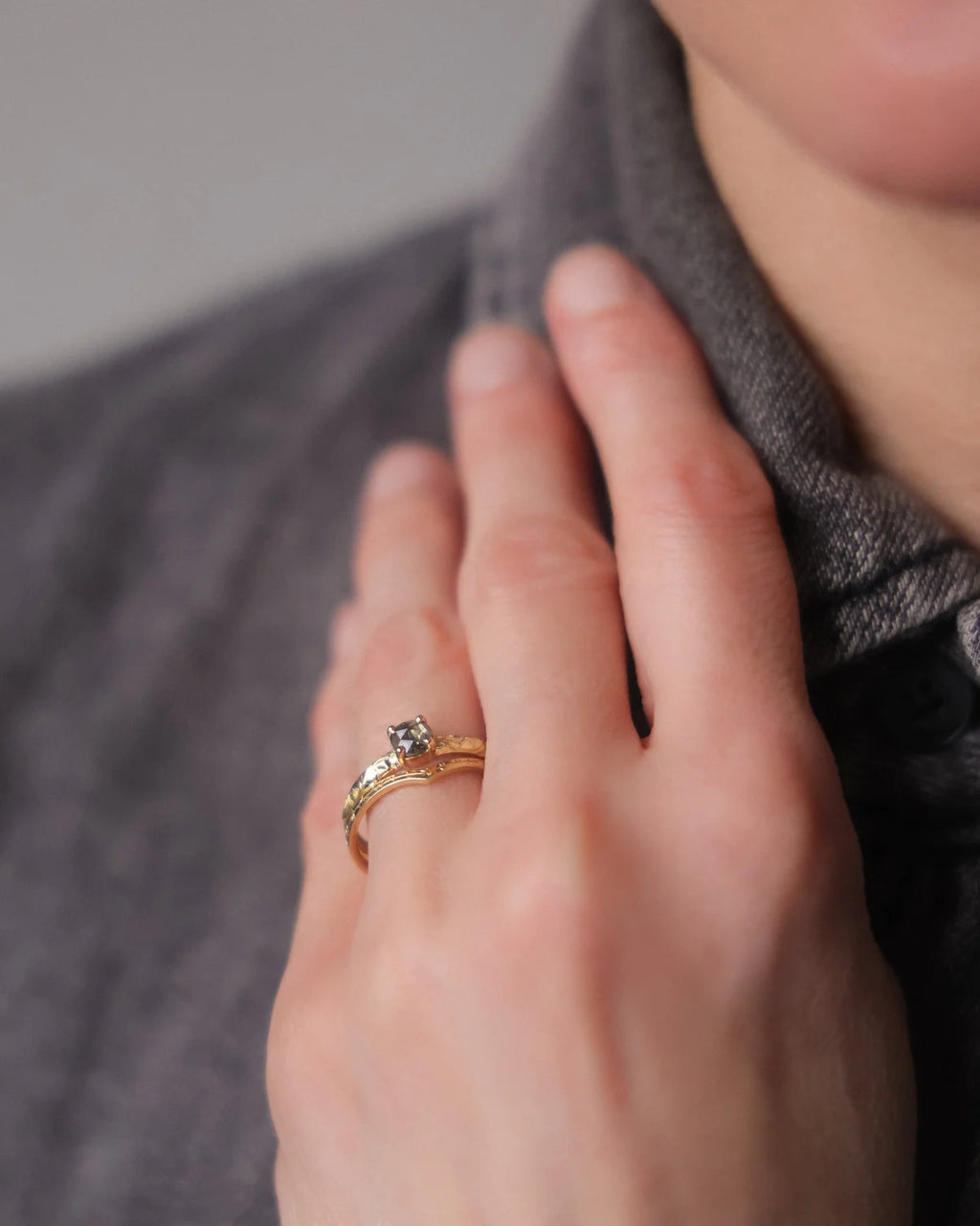 Dark grey rose-cut diamond ring worn with grey shirt