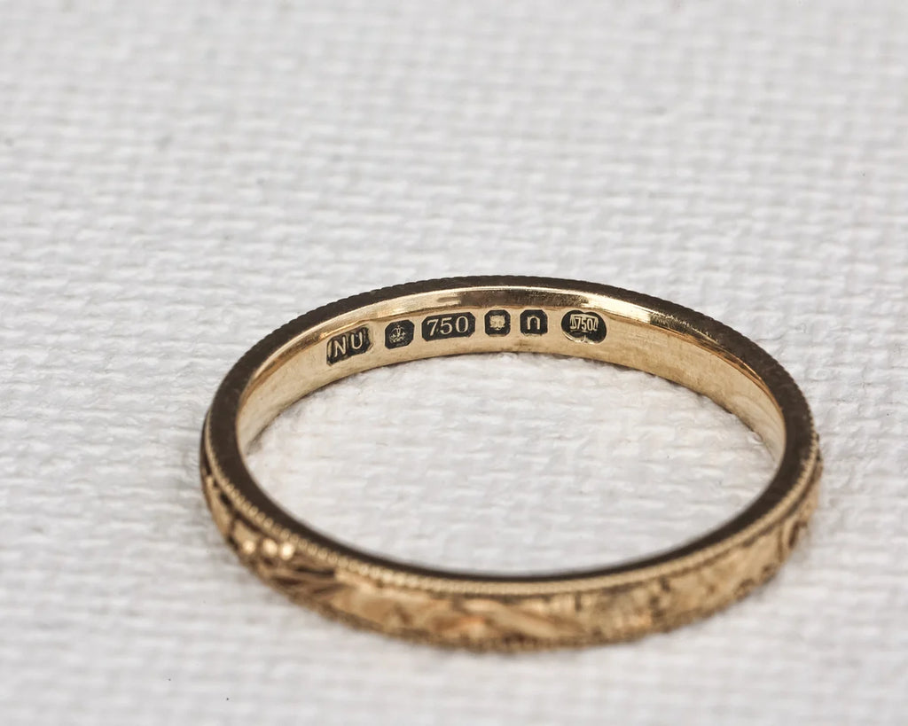 Gold ring with engraved details on a textured white background
