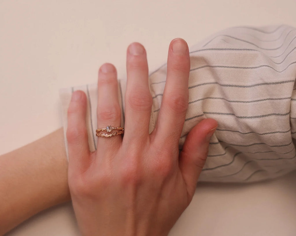 Pale grey rose-cut diamond floral ring worn on hand with striped shirt