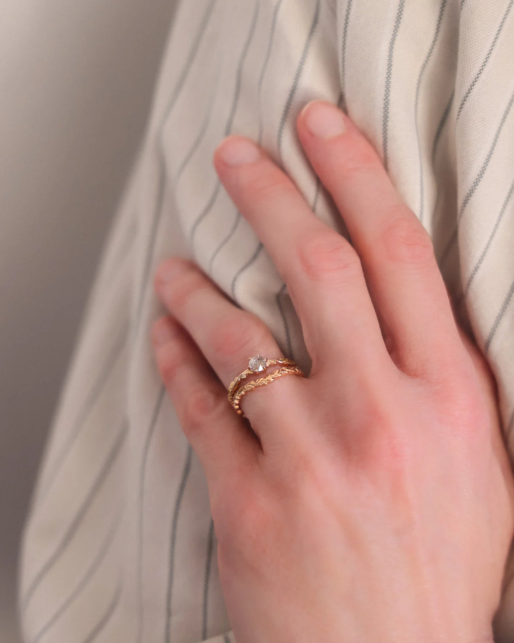 Rose gold floral carved diamond ring worn on hand in soft natural light