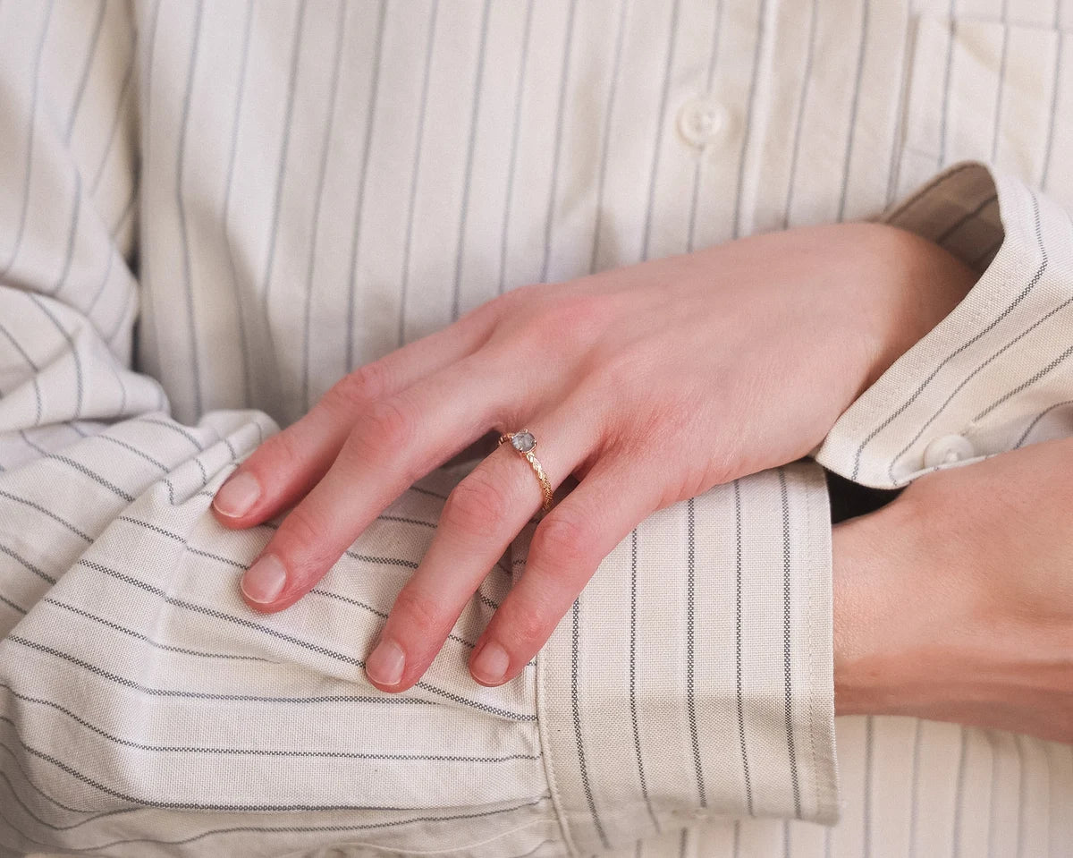 Pale grey diamond laurel leaf ring worn on hand with striped shirt