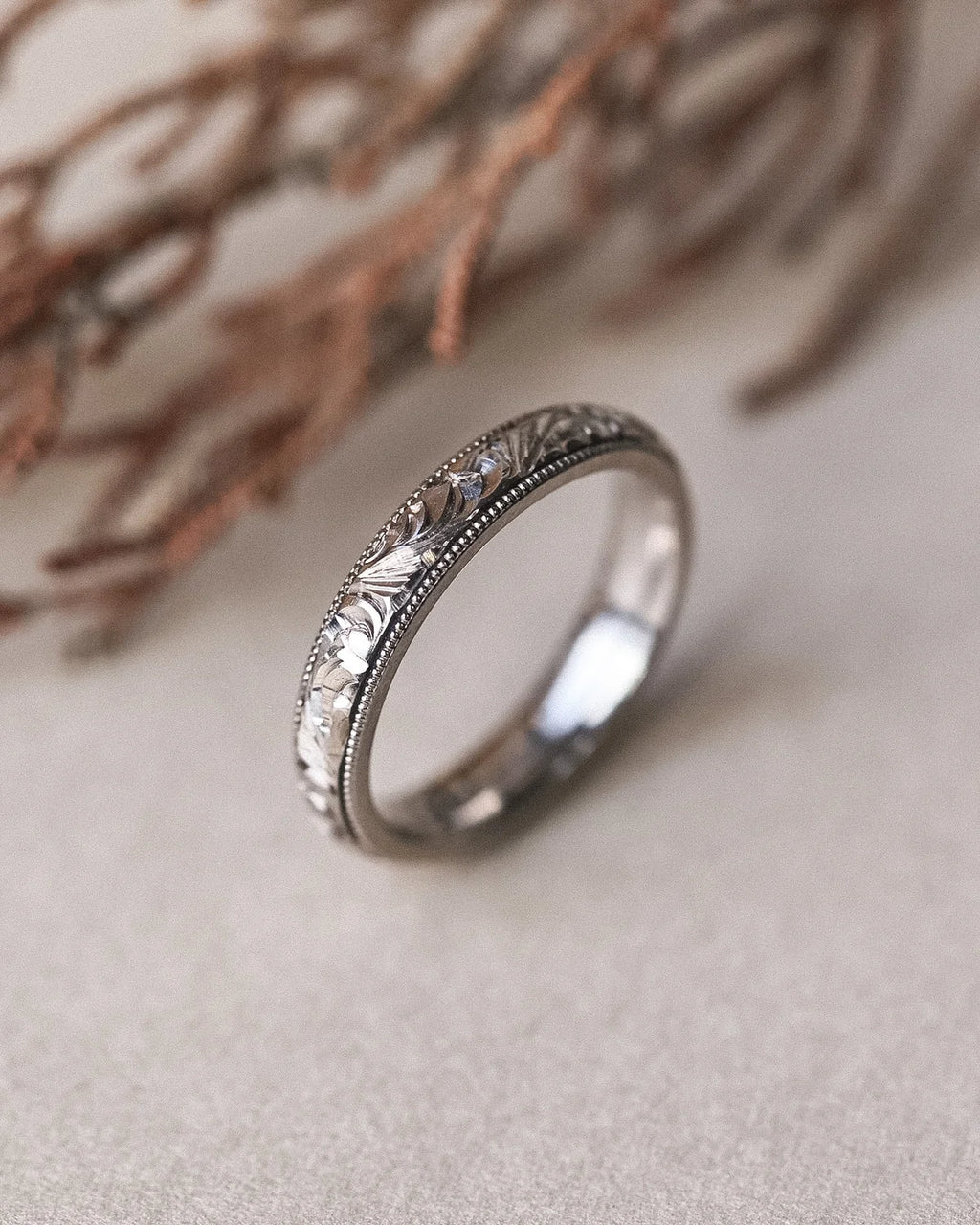Close-up of hand engraved floral motif on white gold wedding band