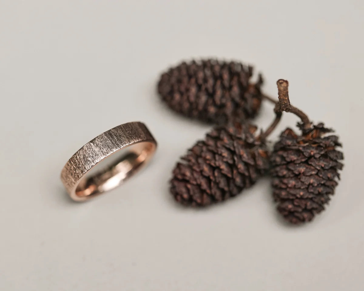 Handmade rose gold horn texture ring styled with pine cones