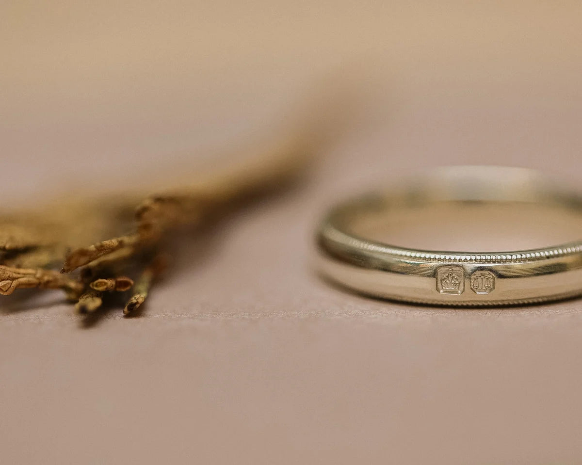 Side view of court shaped wedding ring with hand engraved milled edge