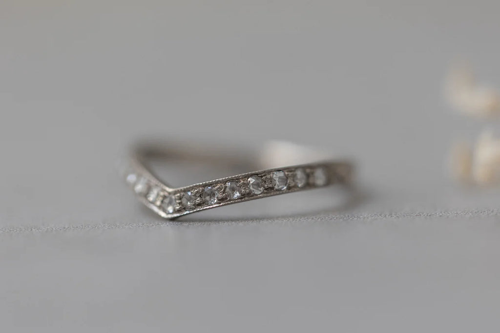 Silver ring with small diamonds on a light gray background