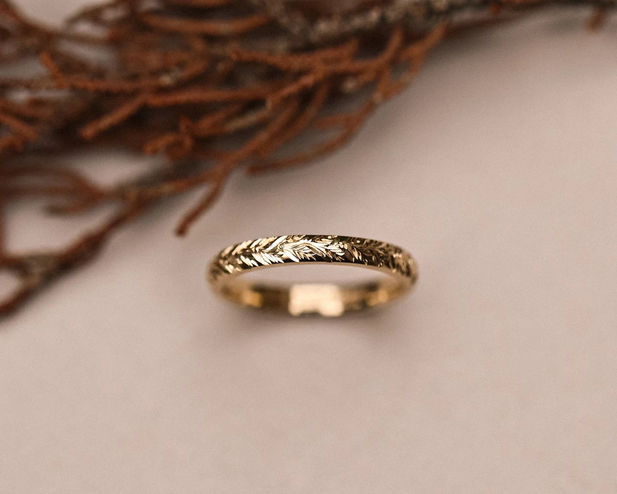 Close-up of 9ct yellow gold laurel leaf engraved wedding ring