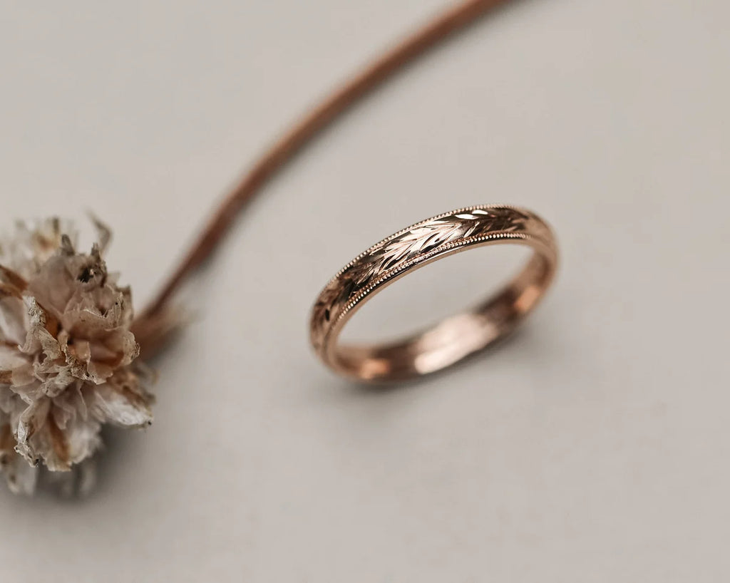 Close-up of hand engraved olive leaf detail on rose gold wedding band