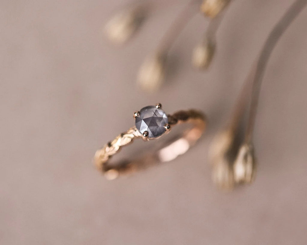 Editorial close-up of rose gold laurel leaf ring with grey rose-cut diamond