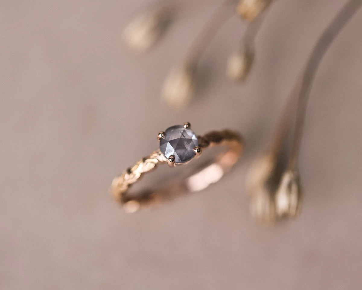 Editorial close-up of rose gold laurel leaf ring with grey rose-cut diamond