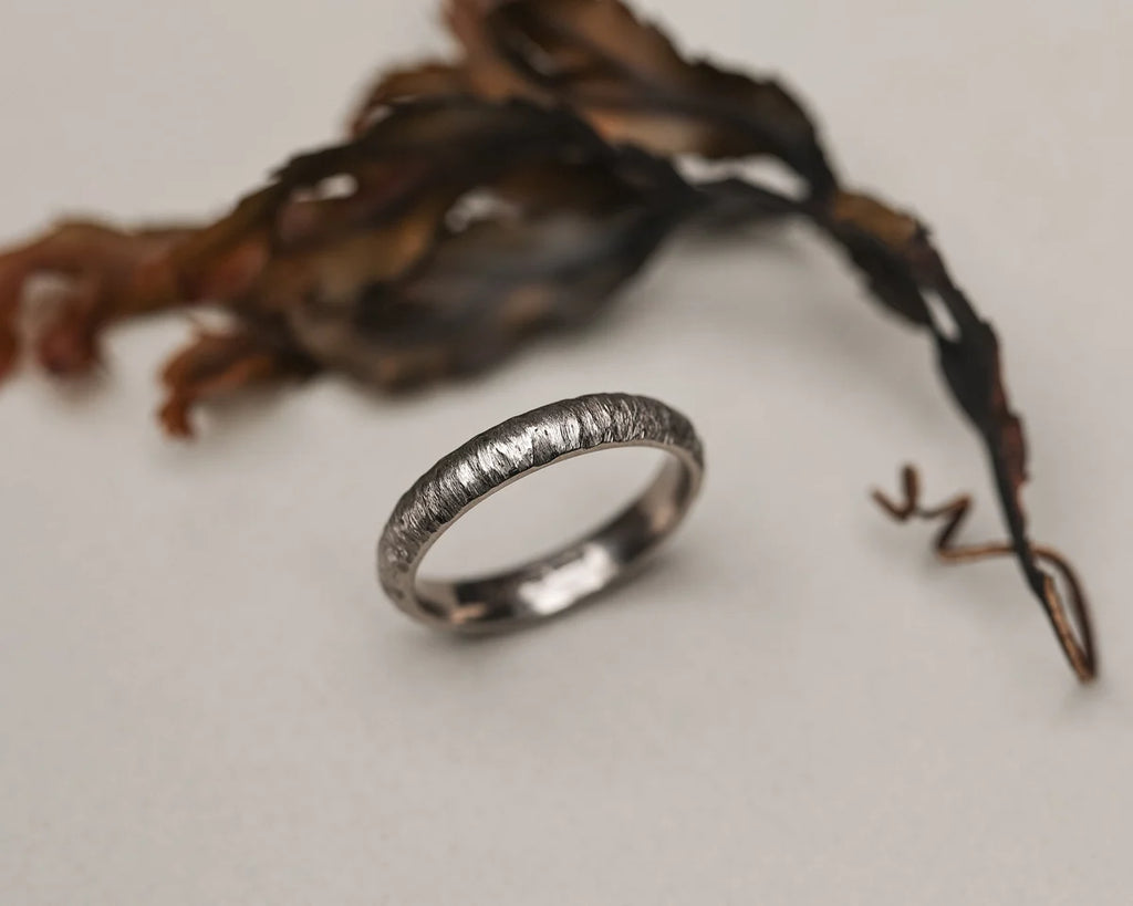 Silver ring with textured design on a light background
