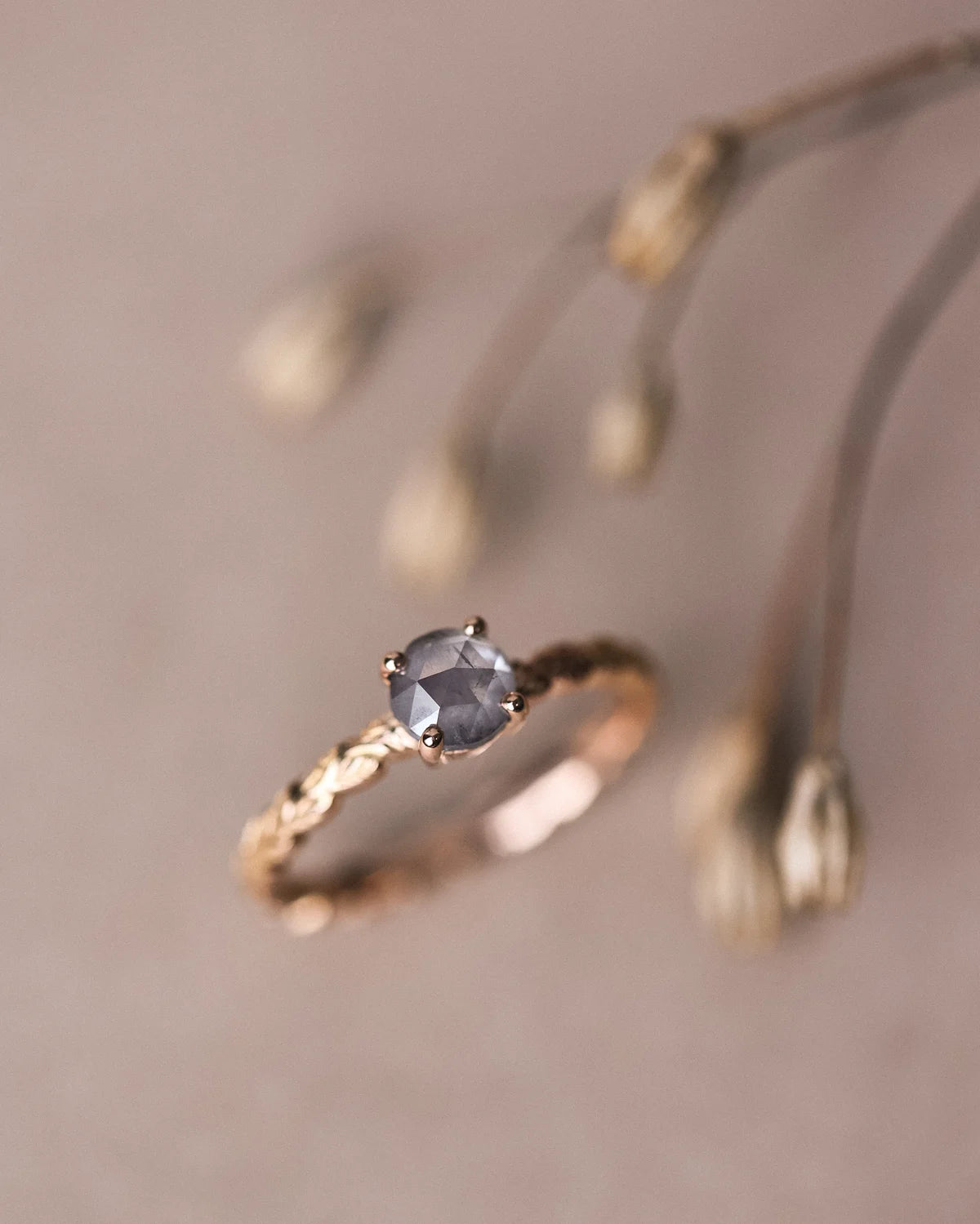 Soft focus close-up of grey rose-cut diamond and carved laurel band