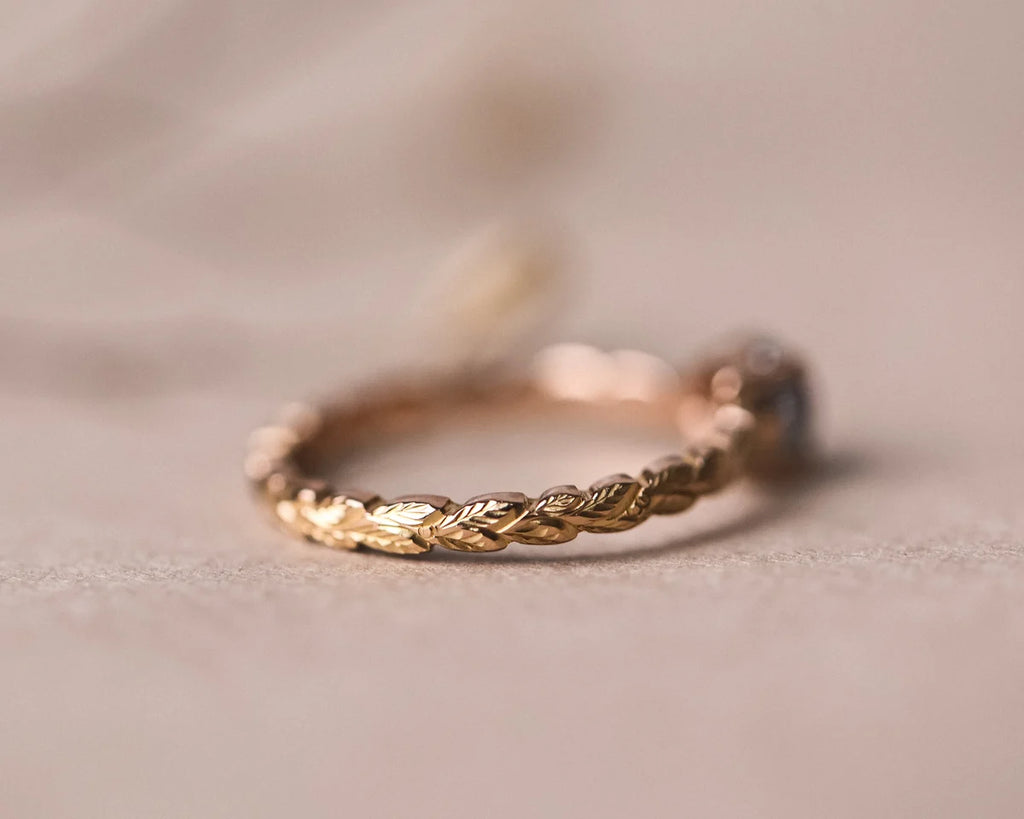 Side view of pale grey rose-cut diamond ring with hand carved laurel band